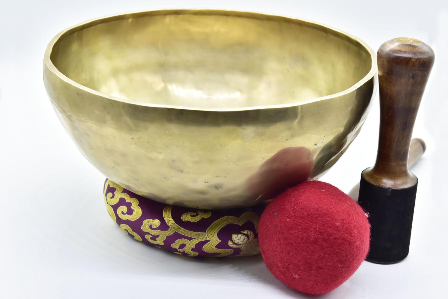 Traditional Himalayan singing bowl with wooden mallet and red cushion