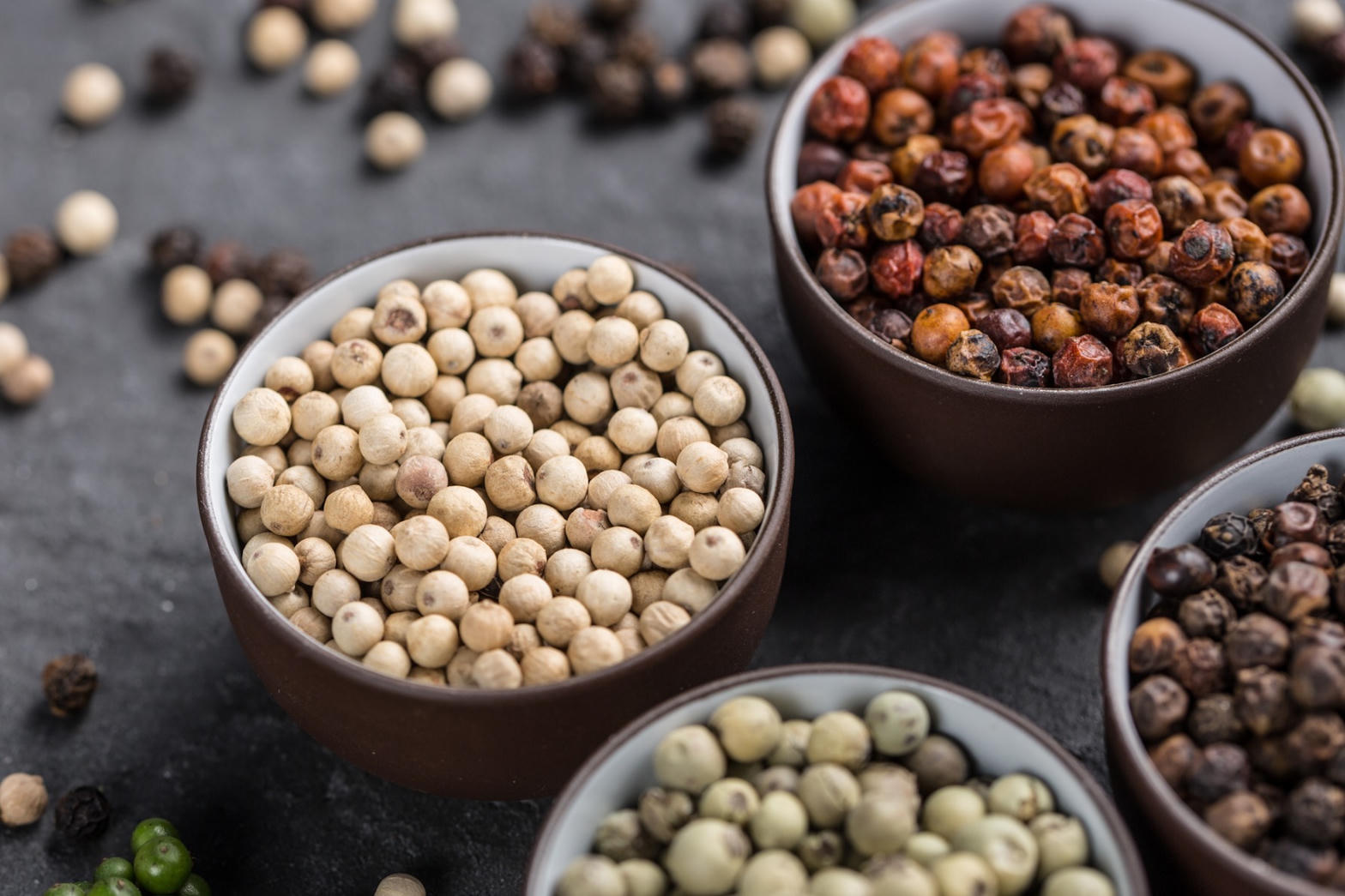 Bowls of white, red, green and black peppercorns