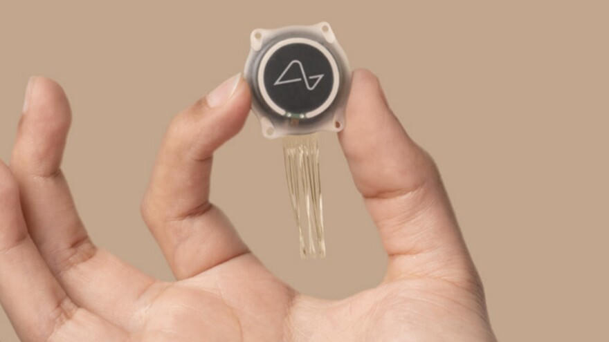 The Neuralink N1 implant held in an open hand
