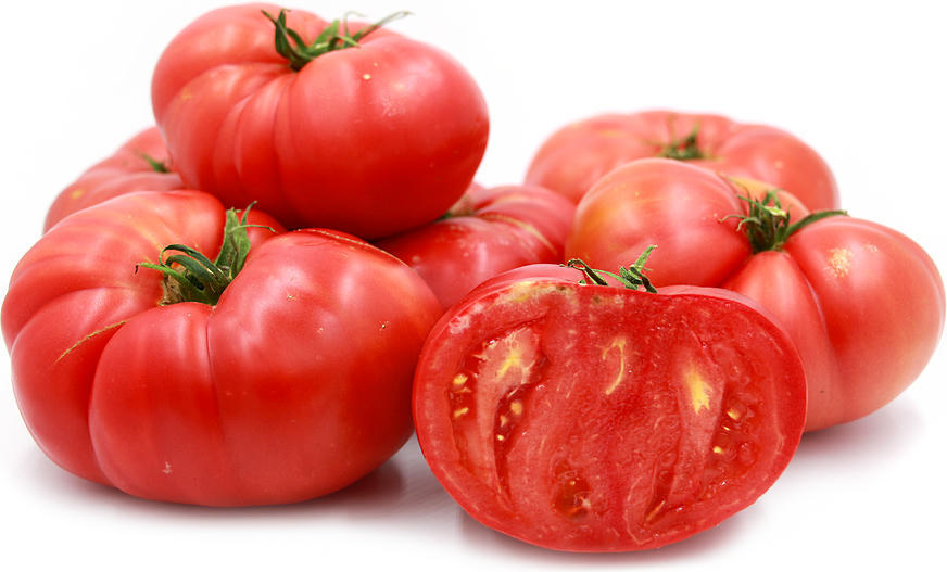 A cluster of ribbed pink Brandywine heirloom tomatoes on a white background, one cut open to show the flesh