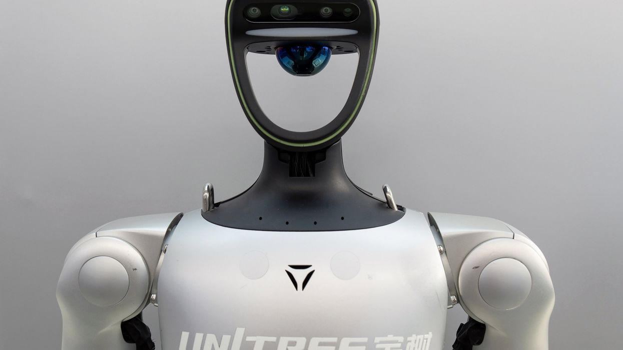 A close-up front view of a white and black Unitree humanoid robot with a ring-mounted sensor head and the Unitree wordmark across its chest.